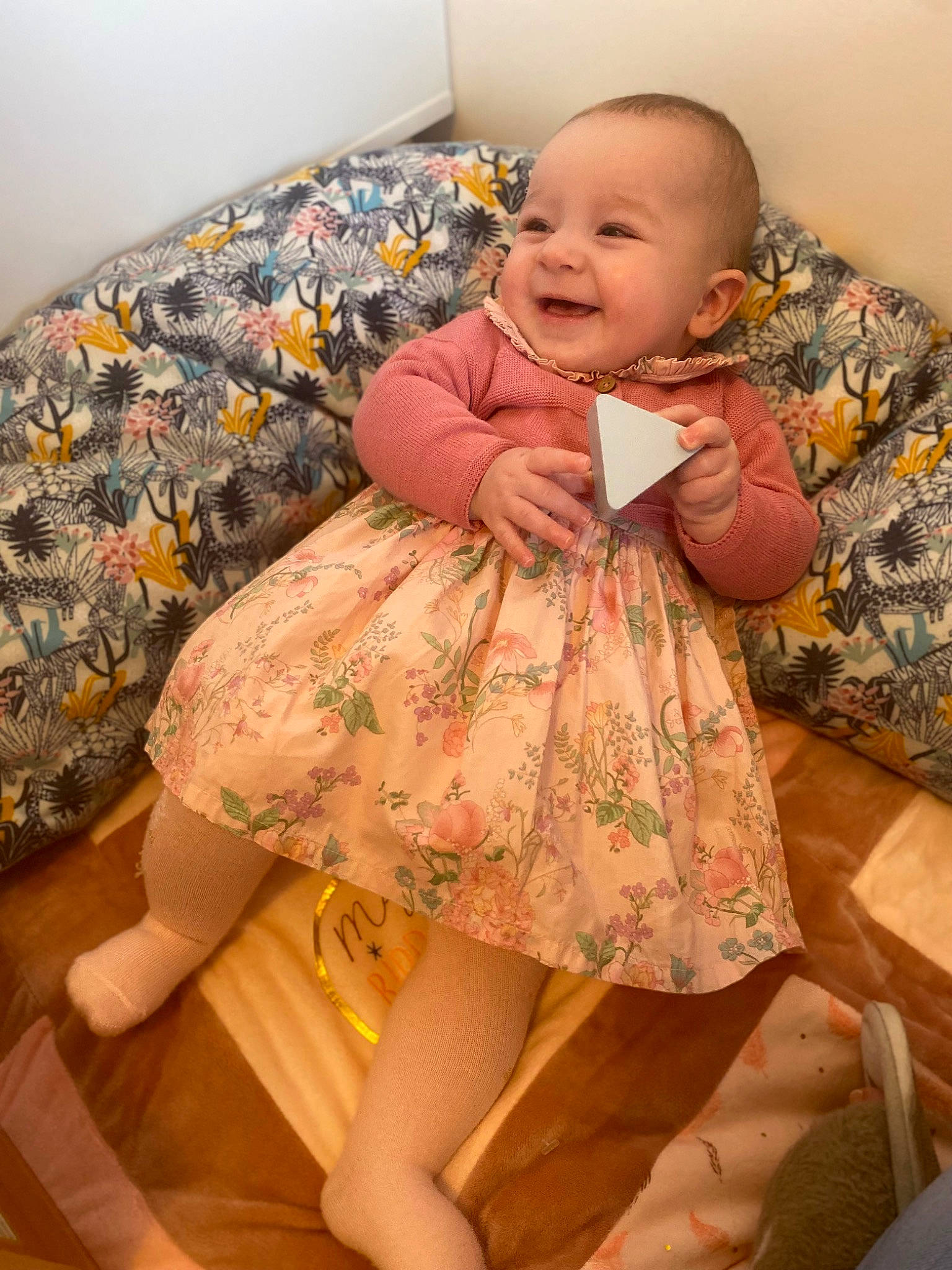 Maria participe au concours pour gagner de l'argent avec cette photo : baby, baby_toddler_clothing, cheek, child, comfort, facial_expression, finger, floor, flooring, human, joint, joy, one_piece_garment, person, pink, skin, sleeve, smile, thigh, toddler