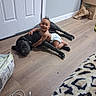 Midknight joined the competition — help win amazing prizes! baby, dog, hugging, floor, diaper, black_dog, indoor, wooden_floor, door, cardboard_box, smiling, pet, animal, child, happy, lying_down, curly_hair, leopard_print, blanket, cable