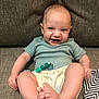 baby, smiling, infant, couch, clothing, diaper, beads, happy, cute, face, feet, hand, sitting, indoors, textile, pattern, fabric, skin, person, portrait