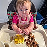 toddler, child, highchair, food, scrambled_eggs, pancakes, toddler_clothing, pink_shirt, face, hands, eating, meal, indoor, plastic_tray, curious_expression, hair, baby, kitchen, home, table