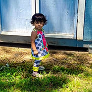 Elsy joined the competition — help win amazing prizes! blue_shed, child, colorful_outfit, curly_hair, daylight, footwear, grass, nature, outdoor, person, polka_dot, serious_expression, shadow, standing, striped_leggings, summer_clothing, sunlight, toddler, wooden_structure, yard