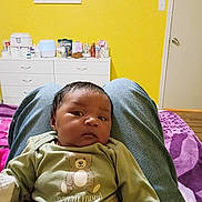 Oliver Smith is registered to the contest to win money with this photo: baby, infant, person, clothing, teddy_bear, green_shirt, jeans, lap, bedroom, yellow_wall, drawer, door, purple_blanket, wooden_floor, baby_essentials, face, hair, indoor, sitting, relaxed