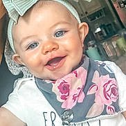 Kamryn is registered to the contest to win money with this photo: baby, child, smiling, headband, bow, blue_eyes, bib, floral, indoor, closeup, cute, happy, infant, person, toddler, clothing, portrait, face, skin, young_child