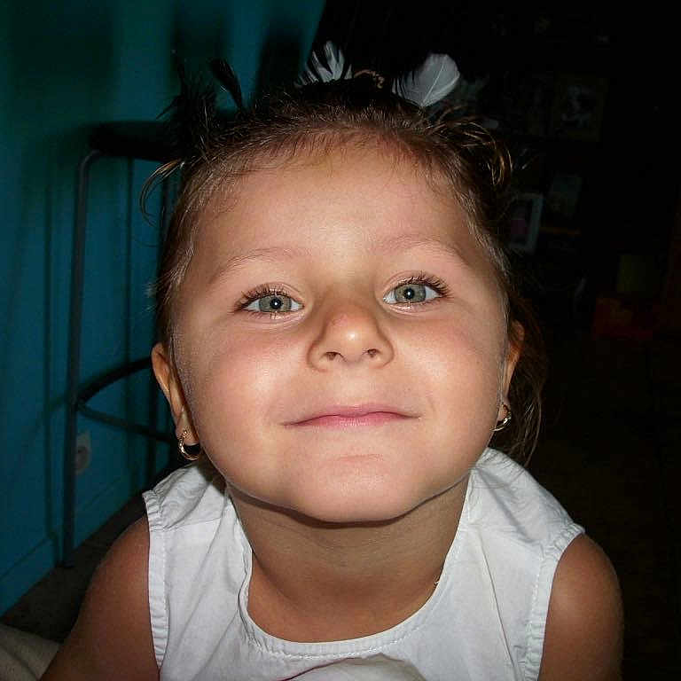 Cassandra participe au concours pour gagner de l'argent avec cette photo : child, closeup, earrings, eyes, face, furniture, girl, hair, happy, head, indoor, person, portrait, room, skin, smiling, stool, wall, white_clothing, young_child