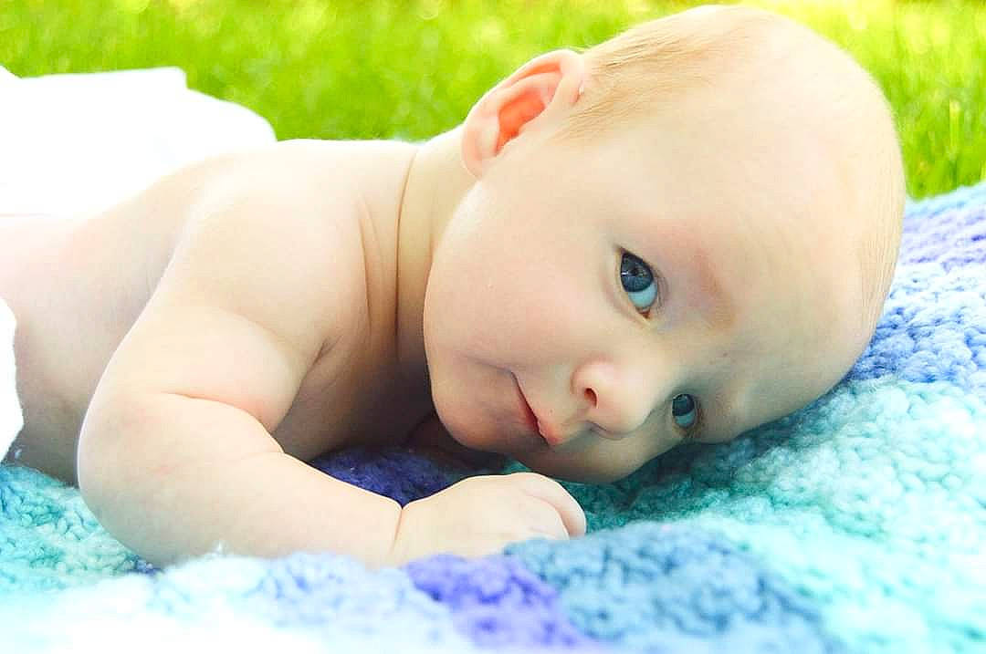 Killian is registered to the contest to win money with this photo: baby, beauty, child, eye, face, grass, head, leisure, lip, nose, person, photography, portrait_photography, skin, smile, toddler, tummy_time