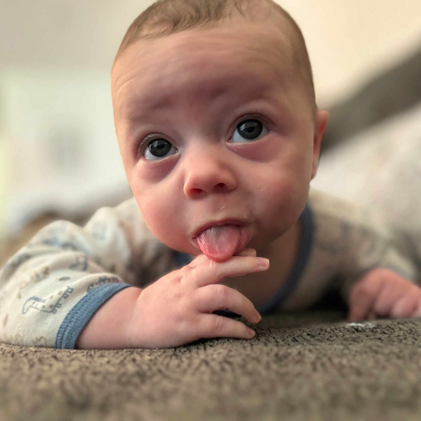 Bohdy joined the competition — help win amazing prizes! baby, blue_eyes, carpet, child, closeup, clothing, cute, expression, face, hand, home, indoors, infant, lying_down, onesie, person, portrait, skin, soft_focus, tongue
