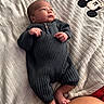baby, infant, blanket, mickey_mouse, onesie, clothing, feet, hands, face, person, soft_texture, lying_down, looking_up, indoor, cute, newborn, skin, warm_colors, cozy, child