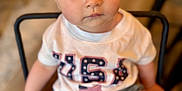 Emelia is registered to the contest to win money with this photo: baby, bandana, chair, child, closeup, cute, denim_shorts, eyes, face, indoor, innocent_expression, person, portrait, red_bandana, shirt, shorts, sitting, toddler, usa_shirt, wooden_chair