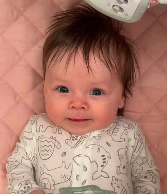 Taylor joined the competition — help win amazing prizes! baby, infant, child, face, eyes, hair, onesie, animal_print, blanket, pink_background, quilted, mobile, toy, cheeks, smile, portrait, lying_down, close_up, nursery, adorable