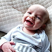 Alijah joined the competition — help win amazing prizes! baby, smiling, infant, cushion, texture, onesie, clothing, hands, face, happy, child, cute, portrait, skin, eyes, mouth, indoor, light, person, relaxing