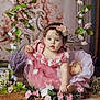 Kimberly is registered to the contest to win money with this photo: baby, child, flower, pink_dress, curly_hair, headband, indoor, portrait, decorative_flowers, green_leaves, flower_arrangement, cute, sitting, face, innocent_expression, soft_lighting, toddler, floral_theme, photography, dress