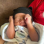Sevyn is registered to the contest to win money with this photo: arms_up, baby, black_hat, blanket, couch, cozy, cute, fabric, hat, indoors, infant, newborn, peaceful, portrait, red_clothing, resting, sleeping, small_hands, soft_texture, wrapped