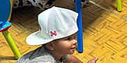 Jason joined the competition — help win amazing prizes! toddler, child, cap, white_cap, sitting, floor, wooden_floor, table, colorful_table, cartoon_characters, toy, plush_toy, cow_plush, smiling, indoor, playroom, shirt, shorts, barefoot, person