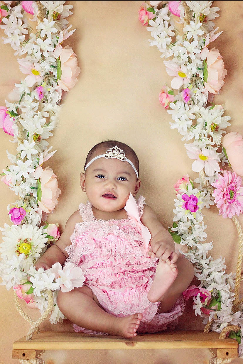 Vaheana participe au concours pour gagner de l'argent avec cette photo : baby, bouquet, chair, cut_flowers, dress, embellishment, floral_design, flower, flower_arranging, happy, headpiece, headwear, jewellery, magenta, person, petal, photograph, picture_frame, pink, plant