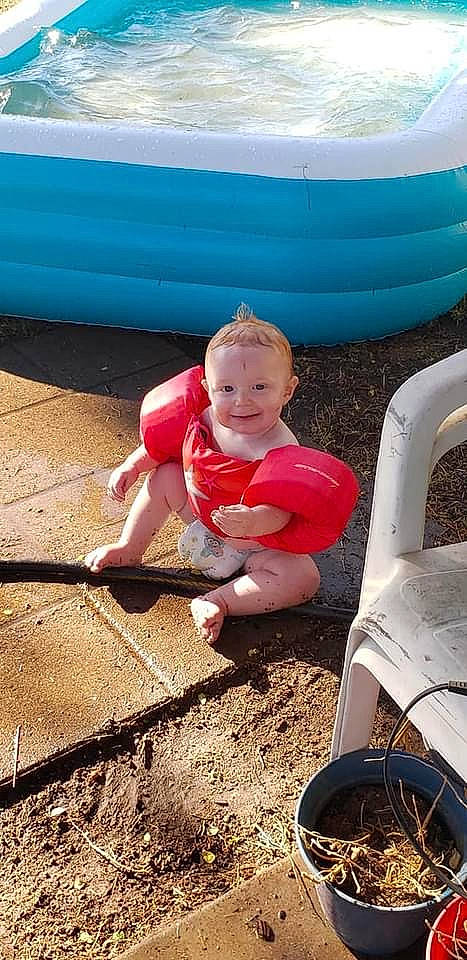 Logan is registered to the contest to win money with this photo: baby, baby_toddler_clothing, blue, child, foot, fun, grass, happy, hat, human_leg, joy, leisure, person, pink, recreation, shorts, sitting, smile, soil, summer