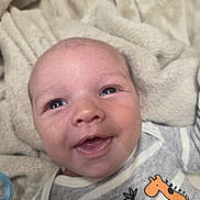 Tiberius is registered to the contest to win money with this photo: animal_print, baby, blanket, cat, child, close_up, clothing, cozy, eyes, face, giraffe, happy, indoors, infant, mouth, newborn, outfit, photography, portrait, smiling