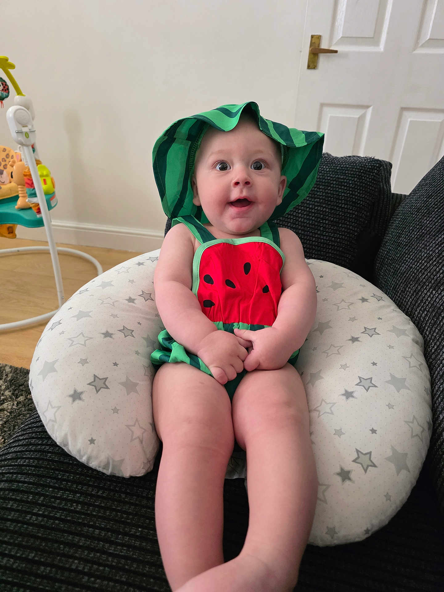 Arlo joined the competition — help win amazing prizes! baby, child, infant, smile, hat, watermelon_outfit, cushion, star_pattern, indoor, furniture, door, happy, person, seated, cute, skin, legs, hands, expression, room