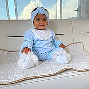 Eva participe au concours pour gagner de l'argent avec cette photo : toddler, child, blue_outfit, headband, white_socks, quilted_blanket, couch, indoor, curtains, window, sky, clouds, smile, cute, portrait, sitting, soft_lighting, baby, homedecor, person