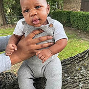 Josiah is registered to the contest to win money with this photo: baby, child, hands, tree, outdoor, grass, sneakers, knitwear, greenery, portrait, cute, person, nature, fence, wood, holding, young, infant, casual, daylight
