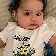 Leonidas is registered to the contest to win money with this photo: baby, child, infant, face, eyes, shirt, clothing, pacifier, blanket, lying_down, curly_hair, expression, cute, indoors, soft_texture, cartoon_characters, three_eyes, green_aliens, white_shirt, person