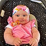 baby, infant, pink_clothing, headband, pacifier, baby_carrier, star_pattern, indoor, furniture, television, fish_tank, child, cute, seated, home, decor, smiling, plush, colorful, relaxed