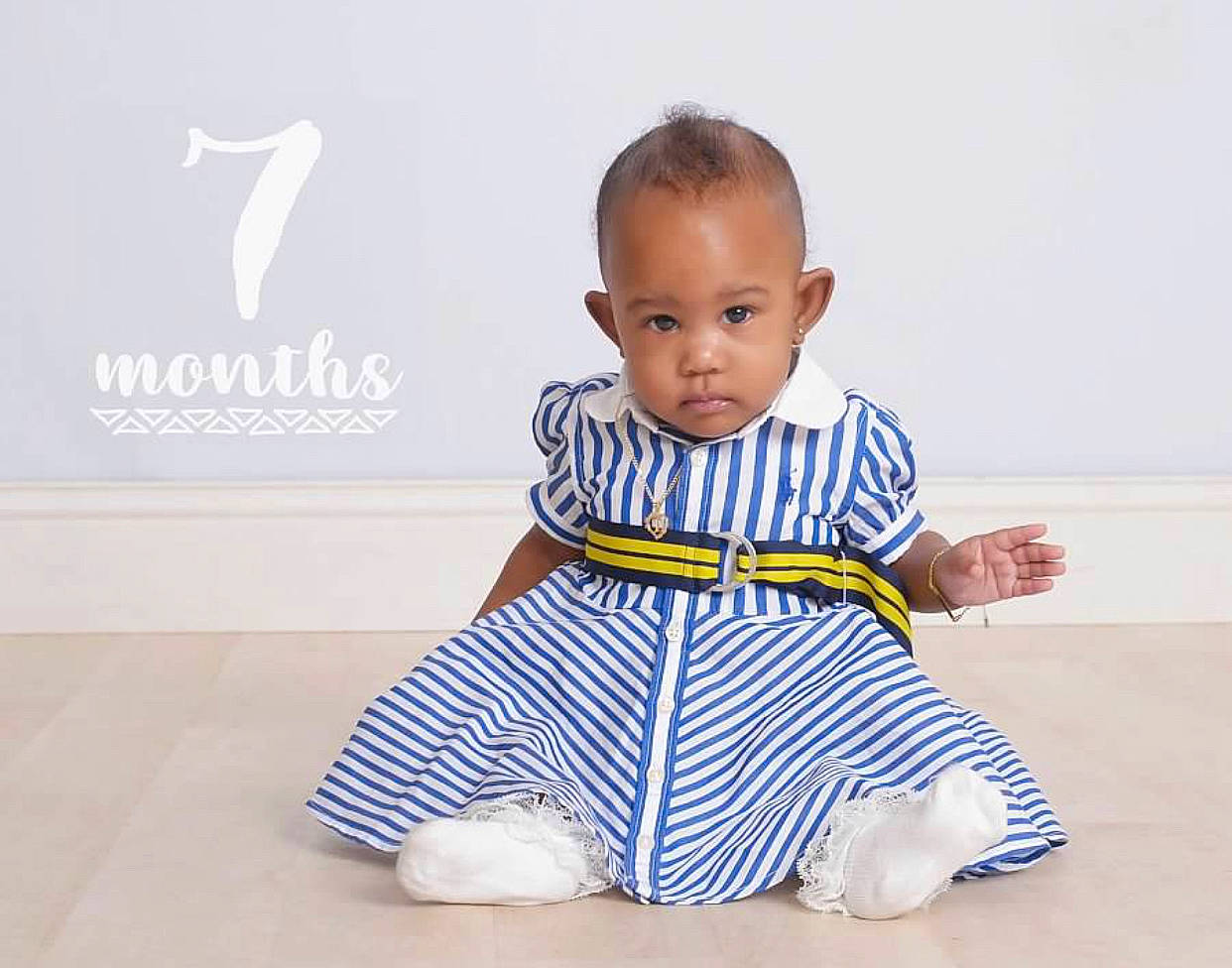 Iyanna is registered to the contest to win money with this photo: baby, baby_toddler_clothing, barefoot, child, electric_blue, face, flooring, foot, happy, head, leg, pattern, person, sitting, sleeve, sportswear, t_shirt, thumb, toddler, white