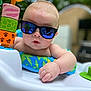 baby, sunglasses, reflection, toy, activity_center, child, infant, hand, face, outdoor, greenery, colorful, playtime, summer, cute, portrait, closeup, expression, skin, casual