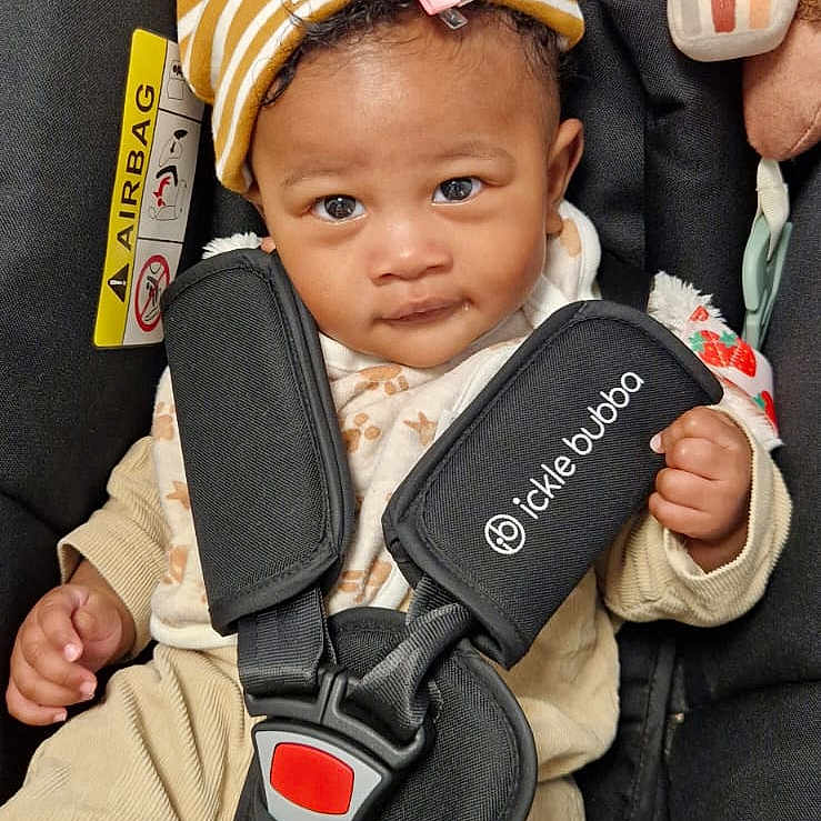 D'Yania is registered to the contest to win money with this photo: baby, black, car_seat, child, clothing, cozy, curly_hair, cute, hat, indoors, infant, looking_at_camera, person, pink_bow, plush_toy, portrait, safety_harness, seat, soft_toys, striped