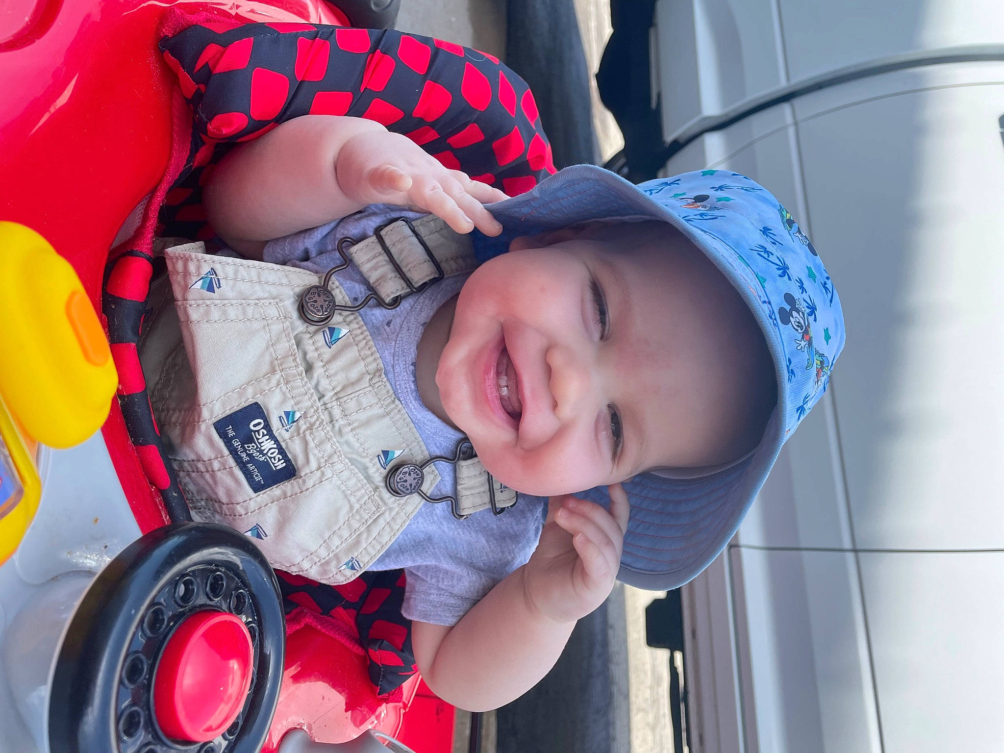 Dawson is registered to the contest to win money with this photo: automotive_tire, baby, baby_carriage, baby_toddler_clothing, baseball_cap, blue, cap, cool, electric_blue, happy, hat, headgear, headwear, joy, person, red, smile, sun_hat, tire, toddler