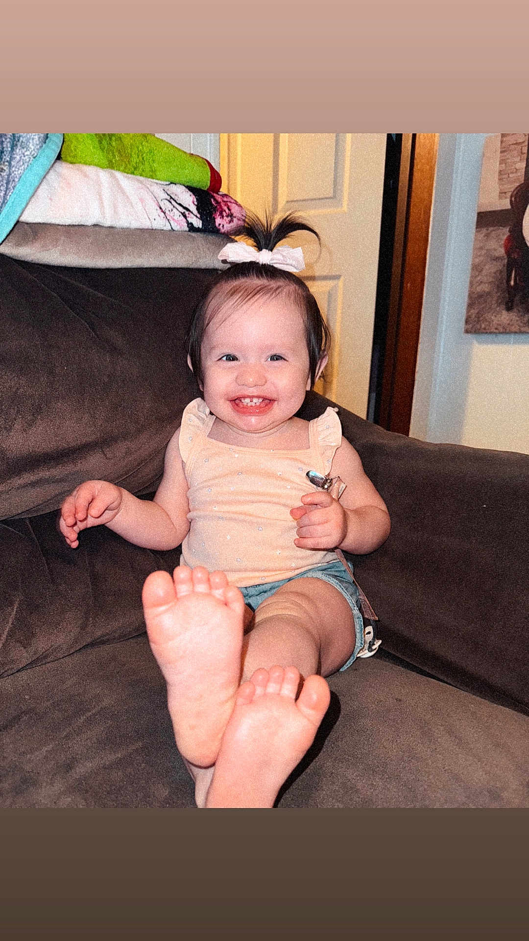 Olivia joined the competition — help win amazing prizes! toddler, child, smile, happy, feet, couch, indoor, clothing, hair_bow, shorts, tank_top, person, furniture, foot, skin, face, pose, cute, young_child, living_room