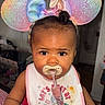 baby, bib, bow, child, close_up, clothing, colorful, dark_hair, eyes, face, glitter, headband, home, indoor, infant, mouse_ears, pacifier, portrait, sitting, smiling