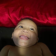 Truen is registered to the contest to win money with this photo: baby, child, smiling, face, portrait, happy, skin, head, eyes, mouth, teeth, infant, red_background, expression, cute, human, closeup, newborn, cheerful, lying_down