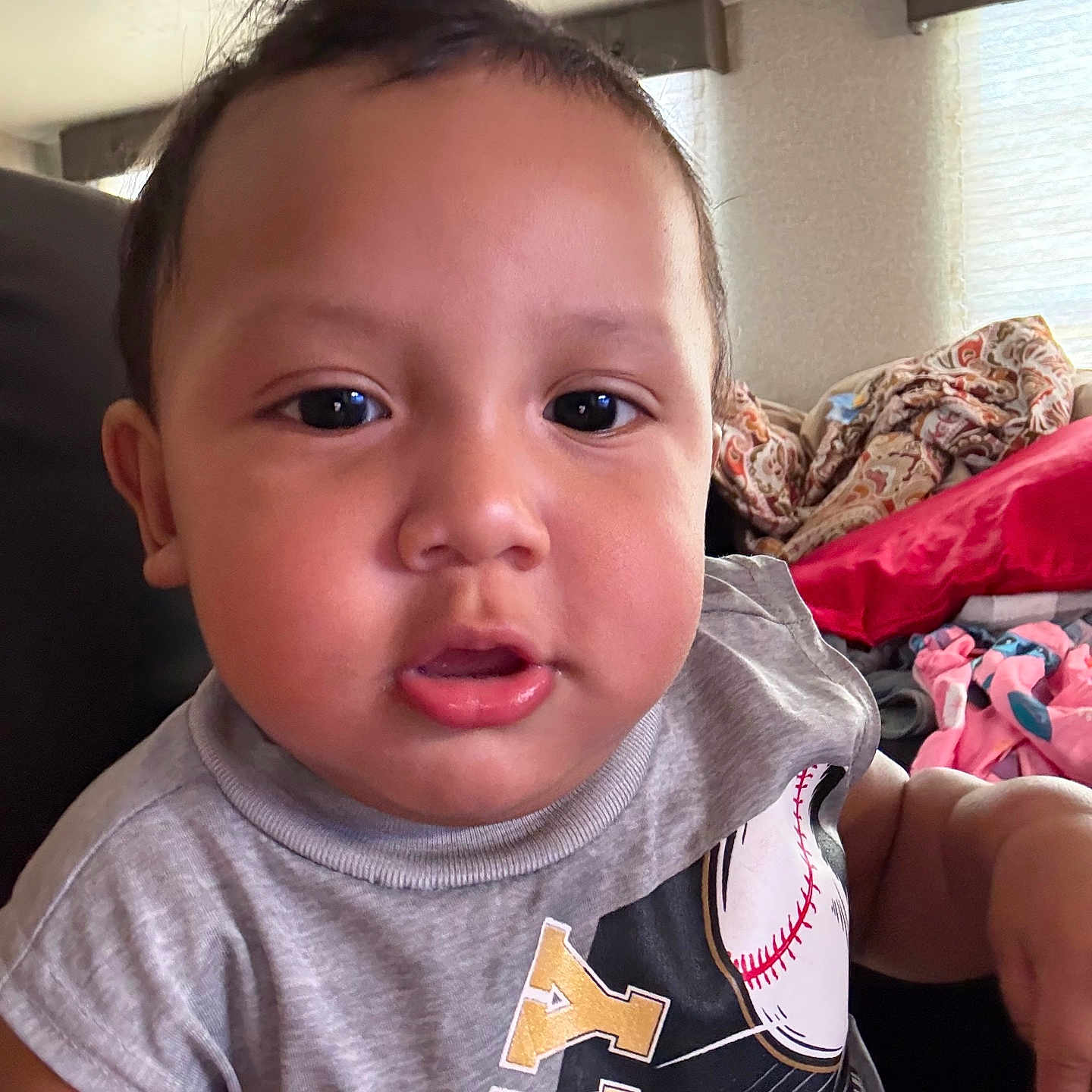Truen joined the competition — help win amazing prizes! toddler, child, baby, face, portrait, indoor, clothing, tshirt, baseball, couch, blanket, curly_hair, skin, expression, person, young_child, casual, sitting, home, relaxed