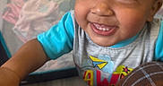 Truen is registered to the contest to win money with this photo: toddler, child, smile, face, eyes, teeth, clothing, shirt, playpen, toy, indoor, happy, cute, baby, person, closeup, hand, floor, colorful, expression