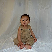 Isaiah joined the competition — help win amazing prizes! toddler, child, baby, overalls, barefoot, sitting, curious, studio, fabric, white_backdrop, portrait, young, innocent, clothing, person, indoor, cute, expression, baby_face, hands
