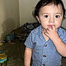 toddler, child, blue_shirt, bedroom, bed, toys, blanket, curious, indoor, person, face, shorts, standing, young_child, home, portrait, expression, hand, fingers, clothing
