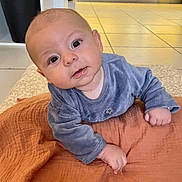 Côme participe au concours pour gagner de l'argent avec cette photo : baby, infant, child, face, eyes, blue_clothing, blanket, orange_blanket, floor_tiles, hand, cute, portrait, indoor, toddler, skin, head, expression, person, lying_down, cozy