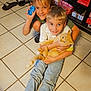 blue_toy, board_games, casual_clothing, cat, child, children, cute, floor_tiles, happy, home, indoor, orange_cat, person, pet, playing, shelf, shoes, smiling, socks, toy