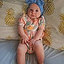 baby, child, infant, headband, blue, romper, floral_pattern, pillow, pineapple_pattern, bed, blanket, skin, legs, feet, hands, face, eyes, cute, indoors, portrait