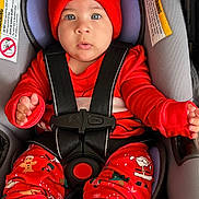 Rosie Mendieta is registered to the contest to win money with this photo: baby, infant, car_seat, red_hat, pom_poms, holiday_pajamas, seat_harness, closeup, portrait, blue_eyes, cute, festive, socks, hands, lips, soft_padding, winter_clothing, warning_label, straps, sitting