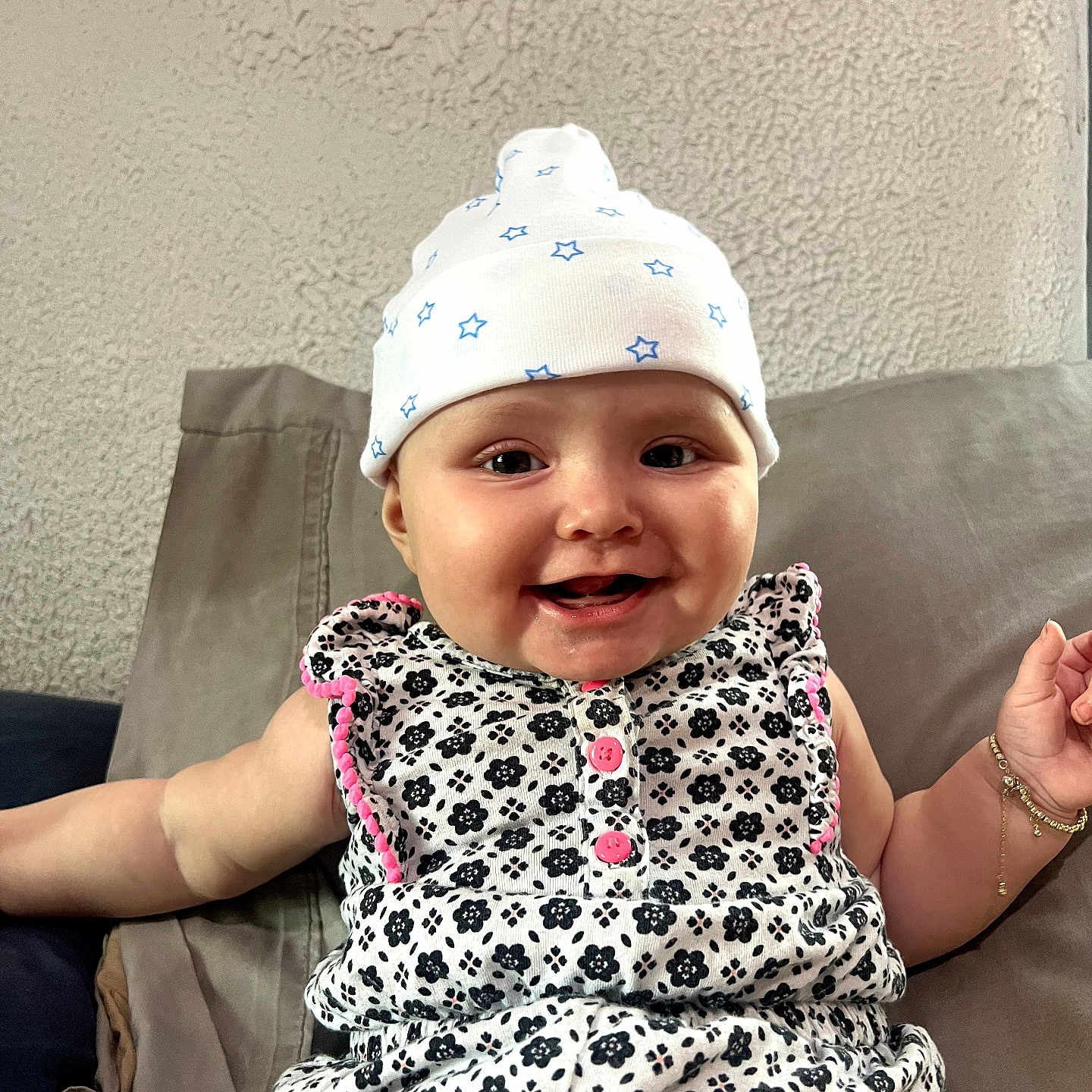Cordilia is registered to the contest to win money with this photo: baby, child, infant, smiling, happy, portrait, indoor, couch, hat, star_pattern, floral_pattern, dress, sitting, close_up, face, eyes, mouth, arm, hand, family_photo
