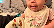 Leilani joined the competition — help win amazing prizes! baby, child, infant, headband, bow, bib, clothing, cute, smile, face, person, indoors, bed, blanket, socks, legs, hand, portrait, happy, toddler