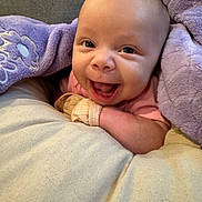 Leilani joined the competition — help win amazing prizes! baby, infant, smile, blanket, purple, cushion, cozy, happy, cute, face, child, newborn, soft, warm, indoor, portrait, clothing, glove, skin, expression