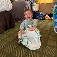 Joshua is registered to the contest to win money with this photo: baby, child, smiling, sitting, plastic_bag, carpet, indoor, bed, clothes, curtains, sunlight, person, happy, floor, room, casual, playful, infant, cute, home