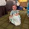 baby, child, smiling, sitting, plastic_bag, carpet, indoor, bed, clothes, curtains, sunlight, person, happy, floor, room, casual, playful, infant, cute, home