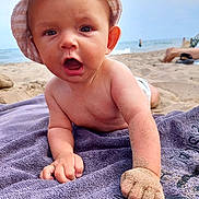 Lian a rejoint le concours — aidez-le/la à gagner de superbes lots ! baby, beach, sand, towel, hat, ocean, water, child, sunhat, outdoor, summer, toddler, skin, hand, portrait, closeup, happy, fun, vacation, nature