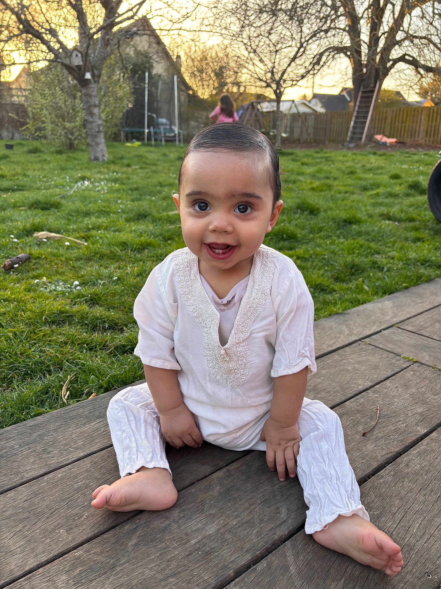 Sohann participe au concours pour gagner de l'argent avec cette photo : baby, child, smiling, outdoor, grass, wooden_deck, sunset, greenery, person, happy, cute, sitting, playground, tree, nature, barefoot, clothing, face, young, daylight