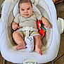 baby, infant, child, smiling, rocker, baby_toy, cushion, clothing, shorts, shirt, floor, tile_floor, home_interior, seat_belt, baby_seat, foot, hand, face, person, indoor