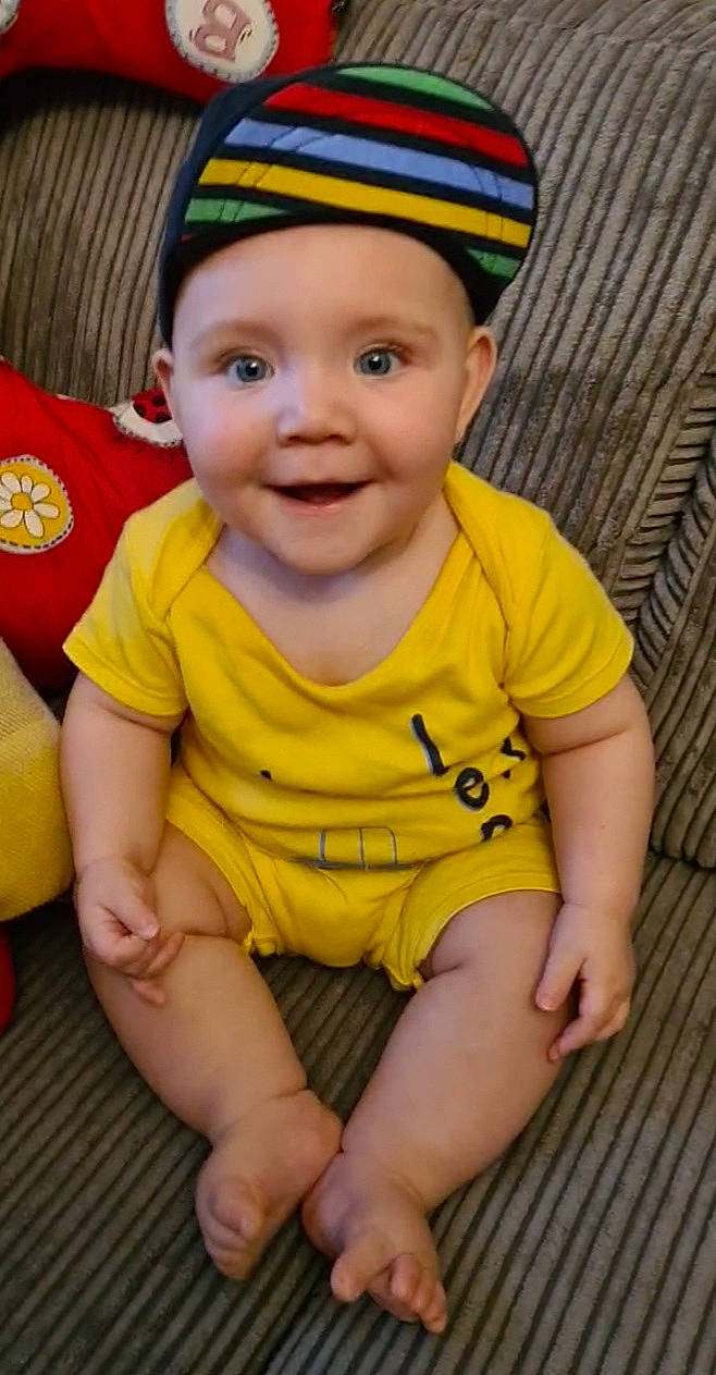 Finnley is registered to the contest to win money with this photo: baby, baby_toddler_clothing, cap, cheek, face, hand, happy, head, headwear, human_body, iris, joy, leg, lip, mouth, nose, organ, person, skin, sleeve