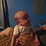 adult_hand, baby, blue_wall, clothing, curtain, face, furniture, hand, heart_pattern, indoor, infant, newborn, onesie, person, portrait, ring, room, skin, wall, watch